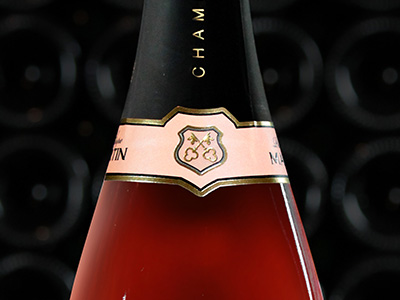 Photo d'une bouteille de champagne rosé posée sur un tonneau